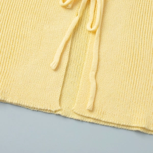 Macro view of light yellow ribbed knit texture and tie-up detail on the sleeve garment