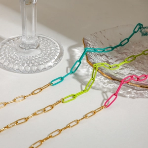 Three-color paperclip chains in gold, neon green, and pink on textured glass tray