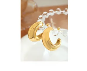 Macro shot of chunky 18k gold plated C-shape hoop earrings with a mirror polished finish