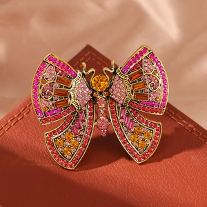 Vintage gold butterfly brooch with colorful crystals on a soft silk and leather background