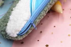 Detail of plush lamb wool pencil case featuring blue zipper and soft green white texture