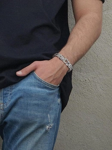 Macro shot of a silver punk titanium steel bracelet with double-row chain on a male wrist