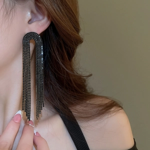 Profile view of model wearing black rhinestone long tassel earrings with U-shaped design