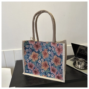 Close-up of small jute tote bag featuring intricate blue and orange floral embroidery