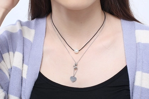 Detail of layered stainless steel necklace with round pearl and engraved heart Love charm
