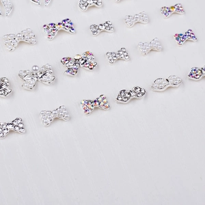 Macro view of silver bow nail charms with pearls and rhinestones for 3D manicures
