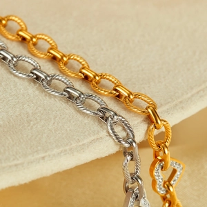 Detail of twisted chain link bracelets in gold and silver with zircon heart charms