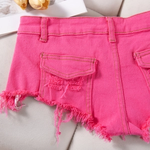 Dettaglio macro di pantaloncini di denim rosa acceso con orli sfilacciati e tasca