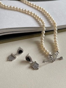 Detail of 925 silver pearl necklace with heart clasp and black zircon drop earrings