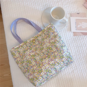 Detail view of floral quilted cotton tote bag with purple straps on a white plaid sheet