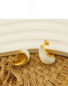 Detailed macro of gold-plated waterdrop earrings with marble texture on hemp mat