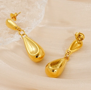 Macro detail of polished 18K gold plated stainless steel teardrop earrings on silk