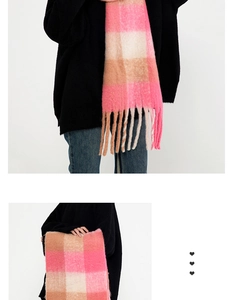 Detail view of a soft pink and beige plaid scarf with fringed edges and wool texture