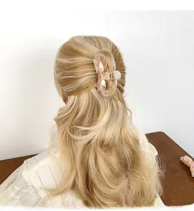 Vue détaillée d'une grande pince à cheveux papillon en acétate marbré sur cheveux blonds