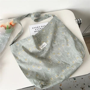 Detail of floral canvas tote bag with yellow feather print and brand label on white table