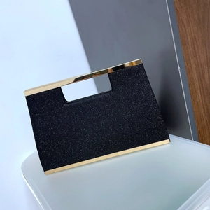 Detail view of black glitter clutch bag with gold metal frame and handle for formal events
