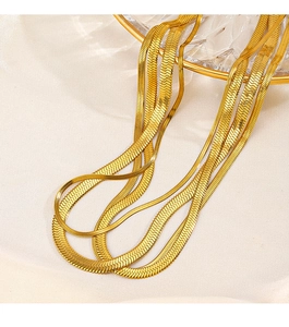 Close-up of golden flat snake chain necklaces on silk fabric with glass decor