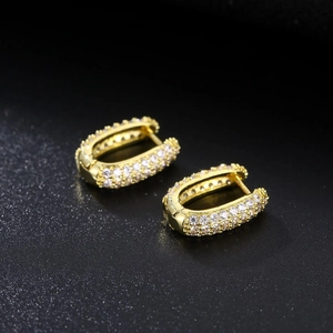 Minimalist gold U-shaped huggie earrings with pave cubic zirconia on black background