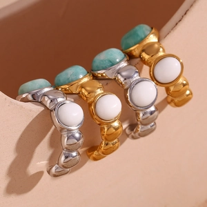 Close-up of gold and silver hammered oval earrings with green and white stone inlays