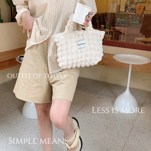 Detail of cream bubble quilted fabric texture and white woven label on canvas tote bag