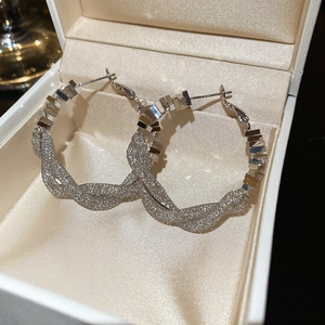 Macro detail of silver twisted mesh and cubic zirconia grid hoops on silk lining