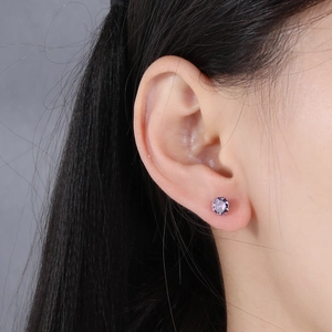 Close-up of a minimalist S925 sterling silver four-prong stud earring with purple zircon