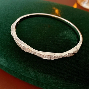 Close-up of silver-tone zircon wave bangle on luxury green velvet background