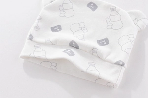 Detail of white cotton newborn beanie featuring grey bear prints and cute soft fabric ears
