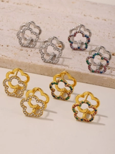 Detail of hollow flower earrings with zircons in gold and silver plating on stone background
