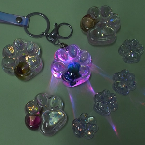 Luminous cat paw resin mold keychain with iridescent effect on dark background