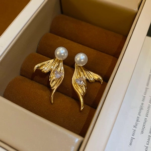 Detailed view of gold fishtail stud earrings with white pearls and heart zircon stones