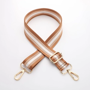 Detail of adjustable thick canvas bag strap with brown stripes and gold metal buckles