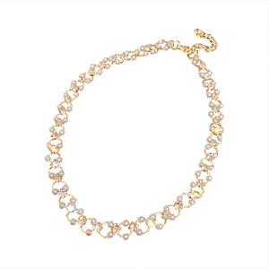 Collier élégant plaqué or avec petites perles blanches et cristaux étincelants sur fond blanc
