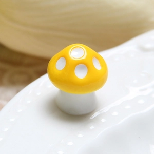 Macro detail of a yellow ceramic mushroom knob with white spots on a decorative base
