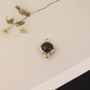 Detailed view of circular black crystal pendant with gold plating and double loops