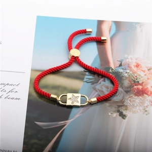 Close-up of red braided rope bracelet with gold star zircon charm and adjustable knot