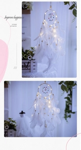 Close-up of handmade white feather dreamcatcher with warm glowing LED string lights