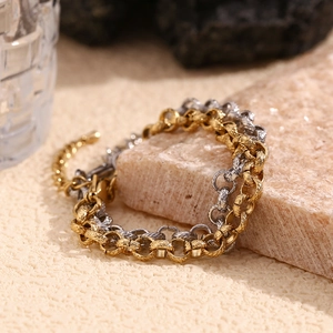 Detail of two-tone gold and silver textured chain bracelet with lobster clasp on stone