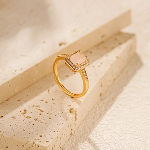 Detailed view of luxury gold ring with pink rectangle zircon on natural stone texture