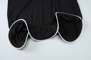 Macro shot of black ribbed knit fabric with white contrast piping and texture details