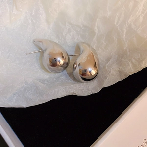 Detailed close-up of silver-tone teardrop stud earrings with a polished smooth finish