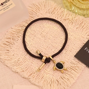 Detailansicht eines goldenen Meeresschildkröten-Anhängers mit schwarzem Stein auf Armband