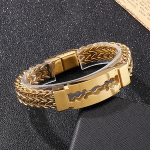 Detail of gold razor blade charm and double wheat chain strap on men's steel bracelet
