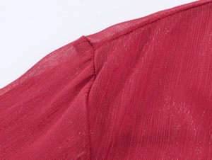 Détail de la blouse en mousseline rouge foncé montrant les plis et la couture d'épaule