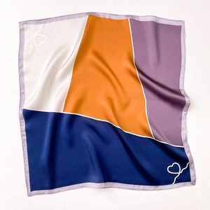 Close-up of the smooth silk scarf texture with geometric color blocks and heart detail
