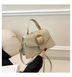 Close-up of sage green leather bag featuring a large golden woven metal buckle detail