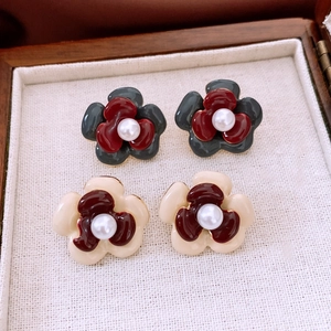 Macro view of double-layered camellia earrings with pearl center in a jewelry box