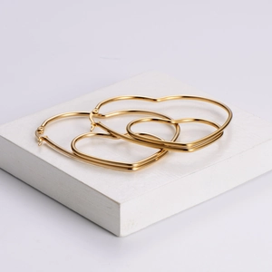 Minimalist gold heart hoop earrings in two sizes displayed on a modern white podium