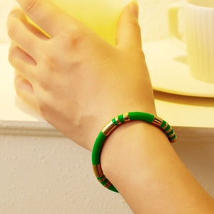 Detail of green and gold bamboo-style titanium steel bangle worn in a lifestyle setting