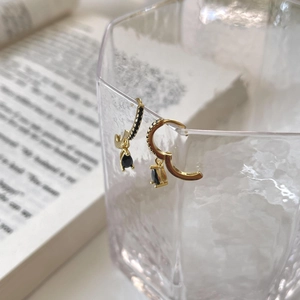 Detail of gold hoop earrings with black zircon drop on a decorative glass rim